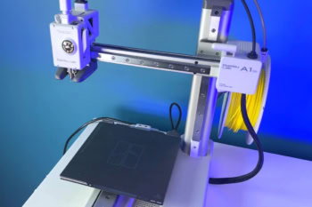 Drukarka 3D Bambu Lab A1 mini z głowicą, stołem i szpulą żółtego filamentu